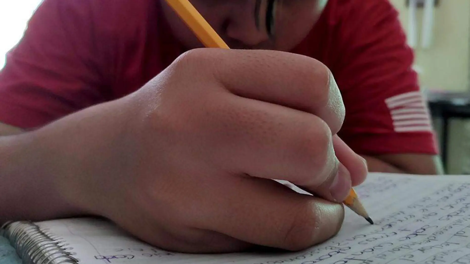 Niño escribiendo con lápiz en un cuaderno